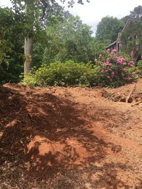 Finished mound of red-clay grindings beside a garden bed of azaleas